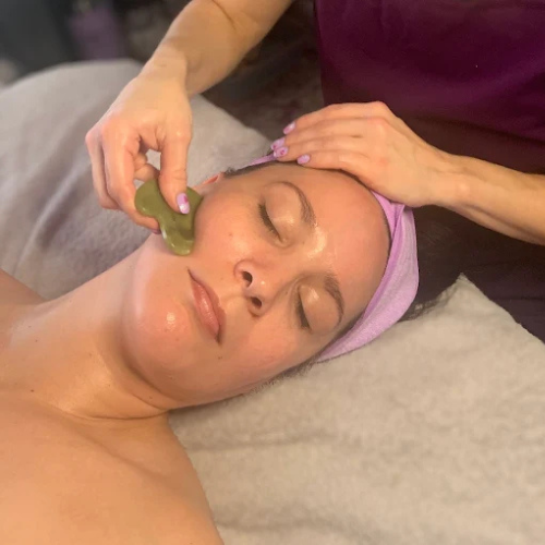 keri giving a massage to a client who is getting a facial treatment